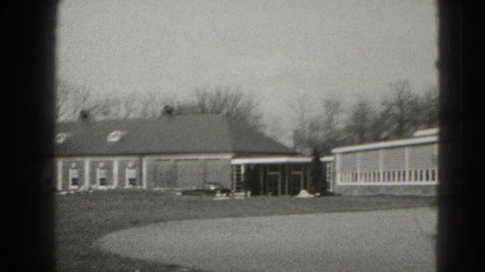 Middletown exterior frame with a low brick building, covered entrance, parked car, bare trees, and open lawn.
