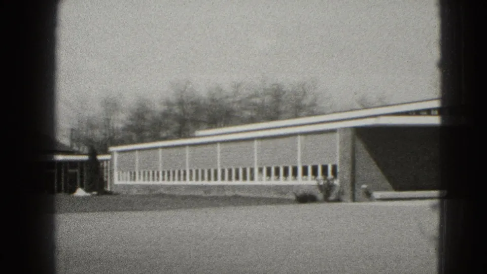 Final Middletown frame showing a long windowed building wing, entrance area, lawn, bare trees, and 8mm frame borders.