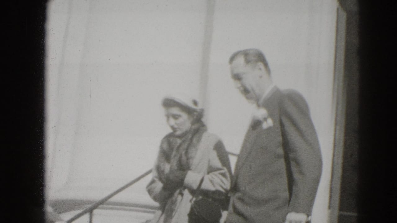 Well-dressed woman and suited man descending exterior steps beside a railing.