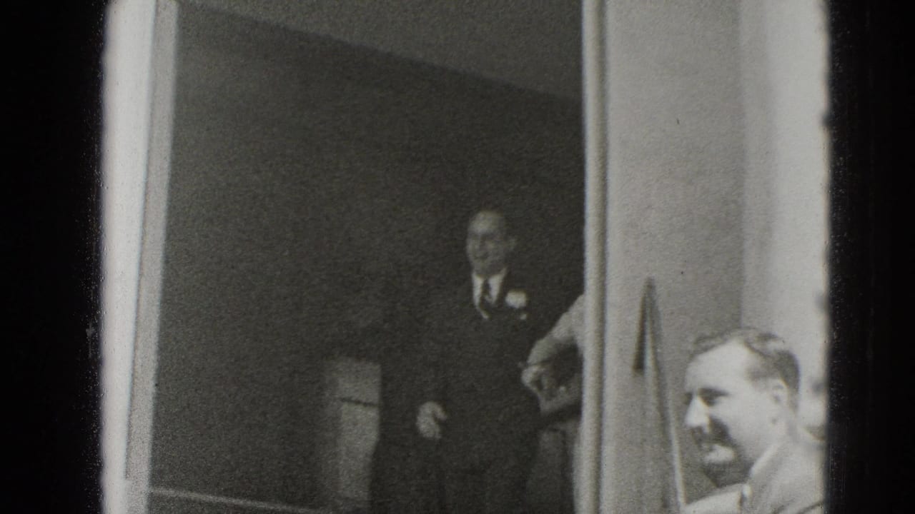 In this Middletown home-movie frame, suited guests wait near a doorway during a 1940s wedding gathering.