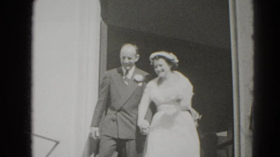 The bride and groom appear outside a Middletown doorway in 1947-era home-movie footage, holding hands after the ceremony.