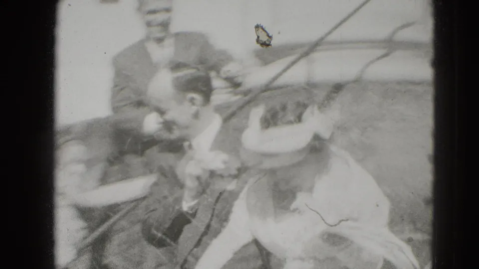 Guests cluster around the newlyweds in a soft 8mm frame, with faces, formal clothing, and a railing visible.