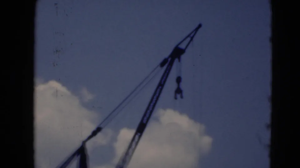 A dark industrial crane boom appears against clouds in 1940s 8mm footage from Middletown, Pennsylvania.