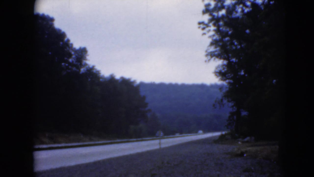 The vehicle continues along a wooded Pennsylvania road, with the lane stretching toward low hills and roadside trees.