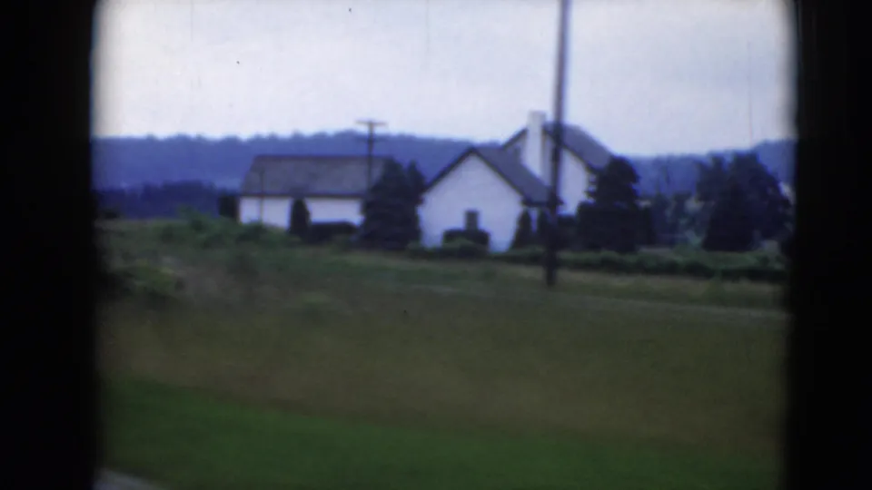 Rural houses, utility poles, and green fields pass by in archival home-movie footage from Middletown, Pennsylvania.