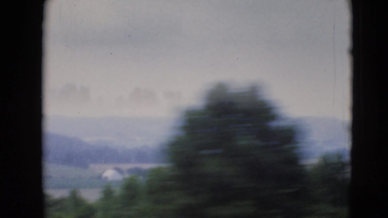 1947 8mm view near Middletown, Pennsylvania, showing blurred trees in front of distant fields and low hills under a pale sky.