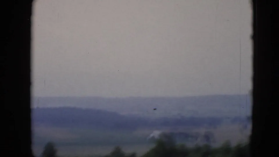Soft 8mm landscape view near Middletown, Pennsylvania, with open fields, distant hills, and a small pale structure at the edge of the frame.