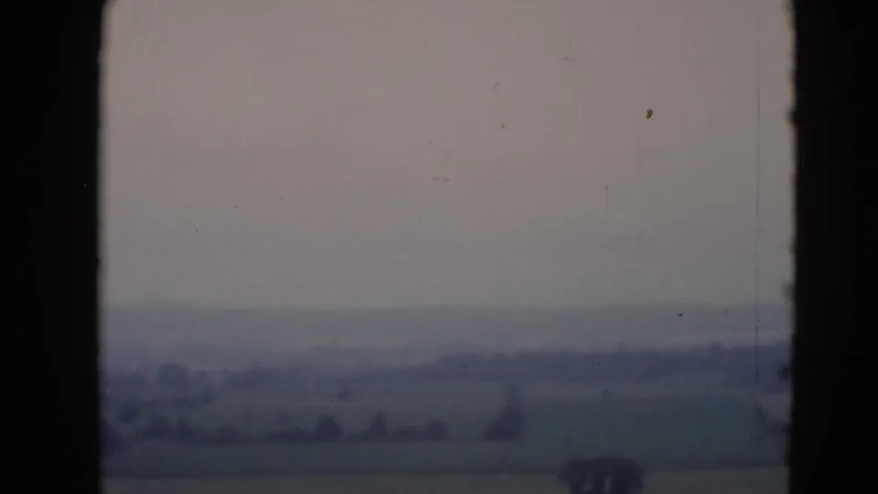 Rural Middletown, Pennsylvania countryside appears beyond dark window framing, with muted fields under a hazy sky.