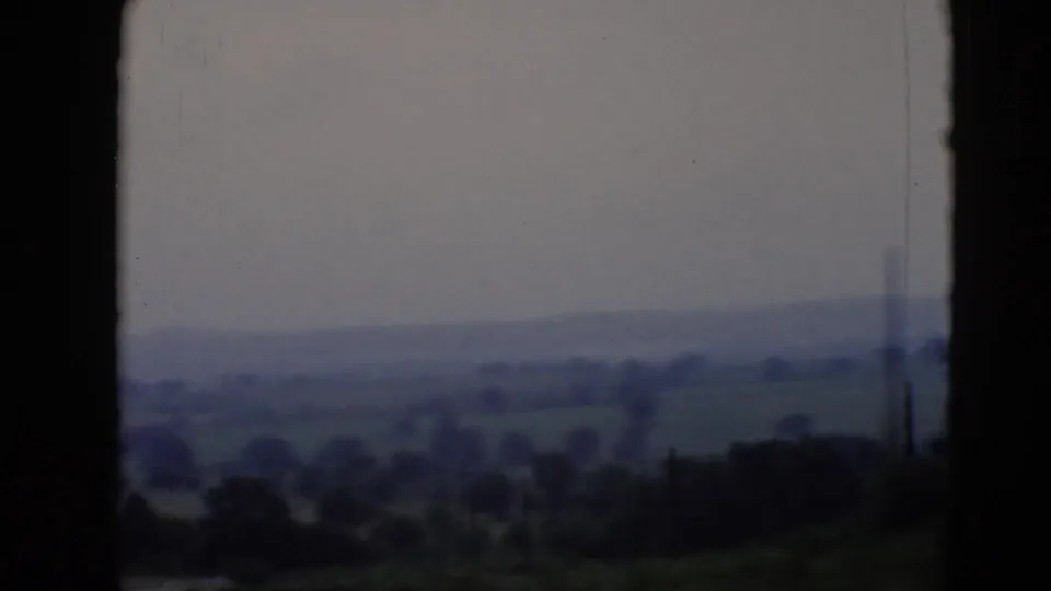 A muted 8mm aircraft-window view shows rolling Pennsylvania countryside with trees, fields, and a hazy ridge line.