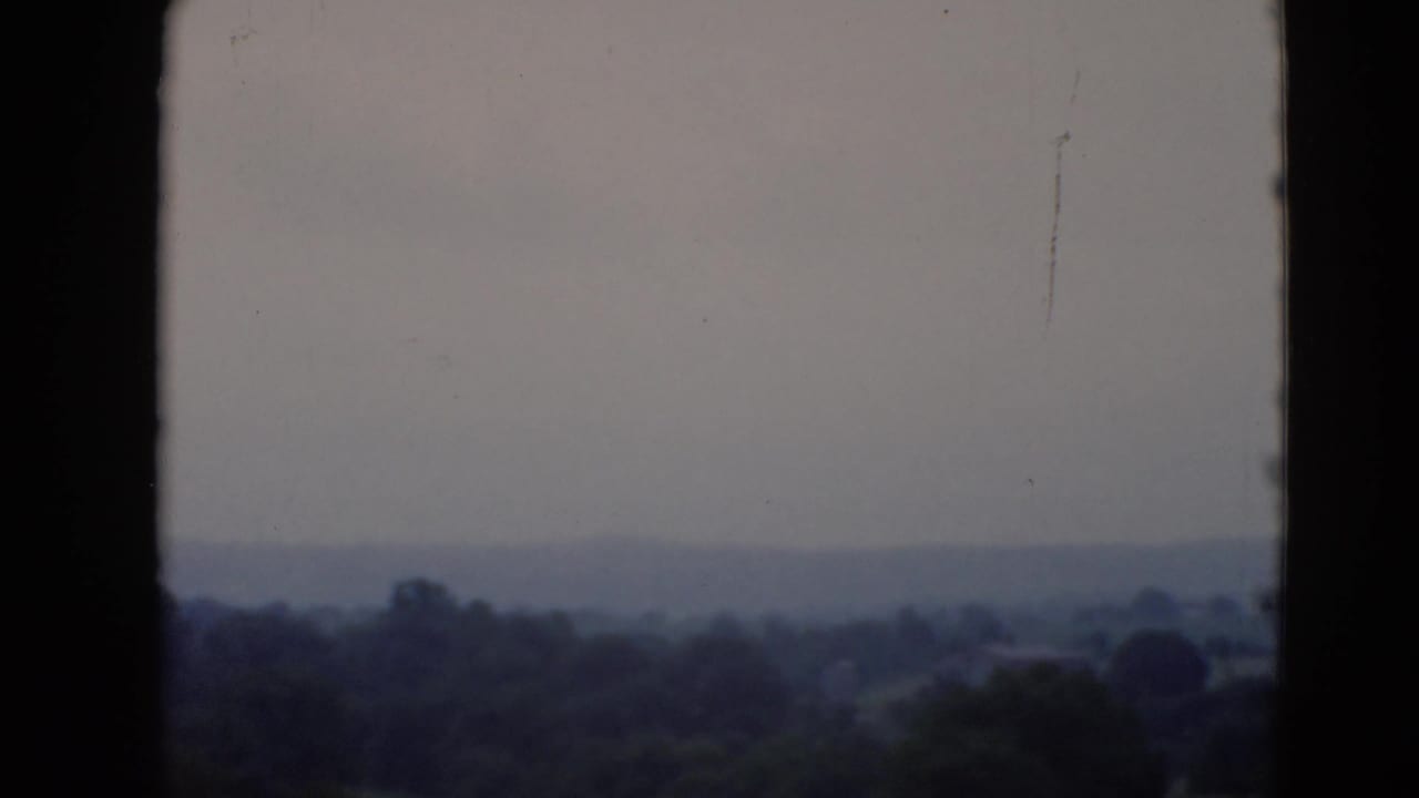 Metadata-dated 1947 8mm view of a hazy Middletown, Pennsylvania landscape with distant trees and a muted sky.