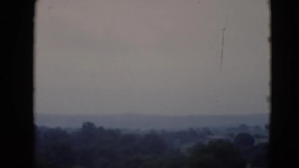 Metadata-dated 1947 8mm view of a hazy Middletown, Pennsylvania landscape with distant trees and a muted sky.