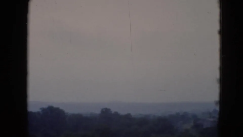 Soft 8mm frame showing a distant wooded Pennsylvania horizon under a pale, hazy sky.
