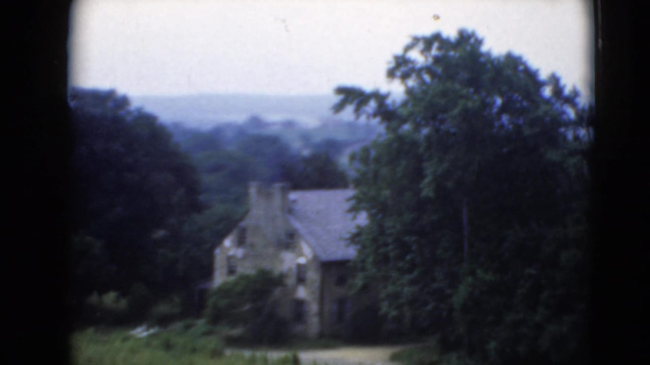Rural Middletown, Pennsylvania view of a stone house among trees and distant hills, filmed on 8mm home-movie stock.