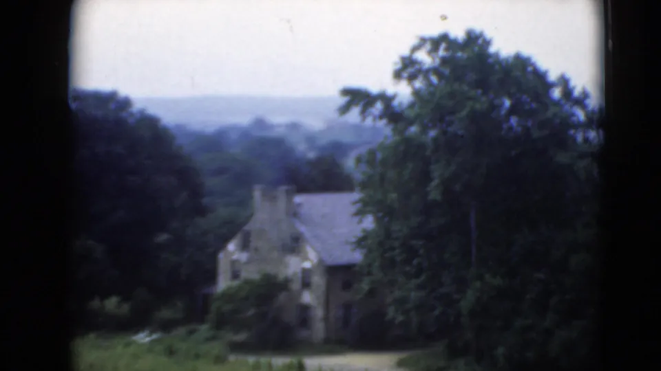 Rural Middletown, Pennsylvania view of a stone house among trees and distant hills, filmed on 8mm home-movie stock.