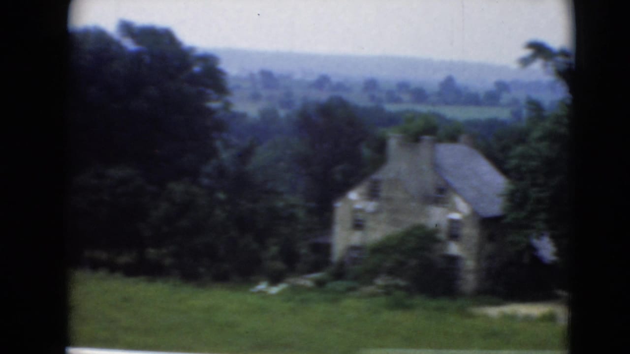 Stone rural house in Middletown, Pennsylvania, seen across grass with surrounding trees and hazy hills beyond.