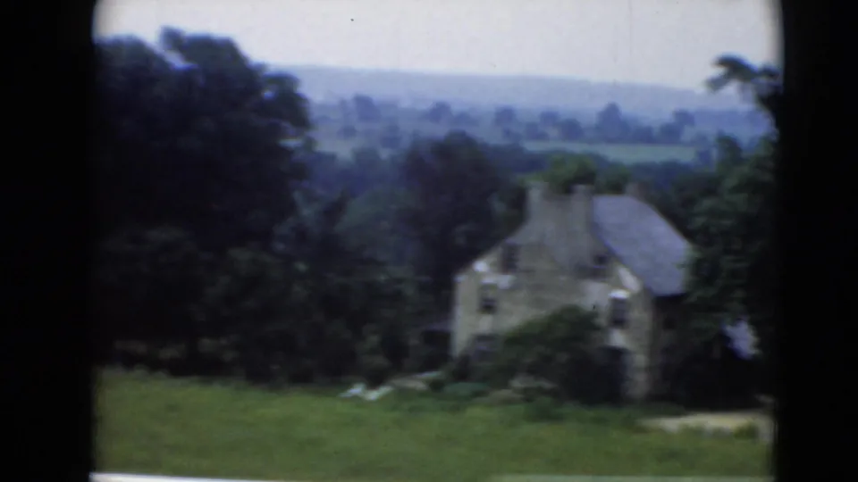 Stone rural house in Middletown, Pennsylvania, seen across grass with surrounding trees and hazy hills beyond.