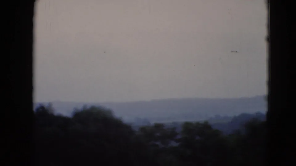 Soft 8mm view over trees toward low hills in rural Pennsylvania, with the house mostly out of frame.