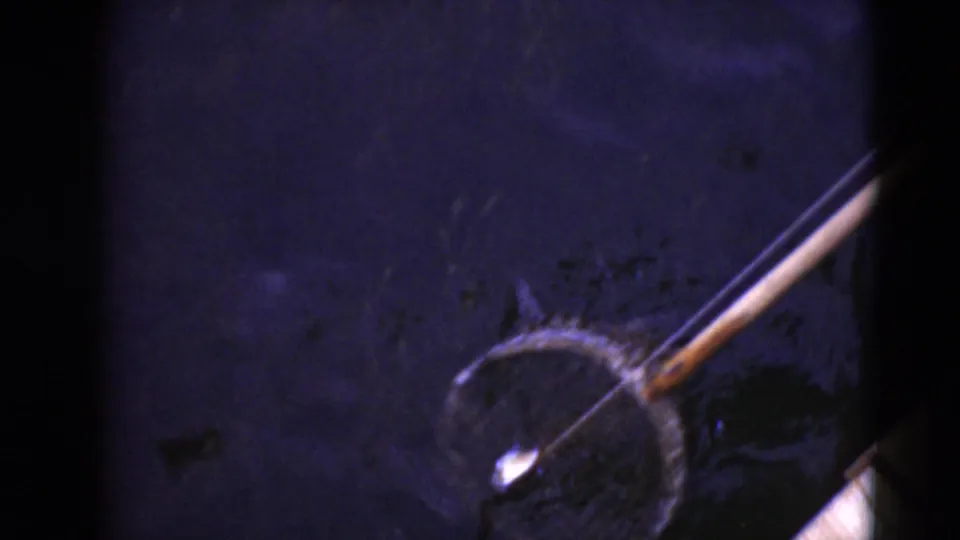 A circular crab net on a pole appears in dark water in this 1940s 8mm home-movie frame from the Middletown, Pennsylvania clip.