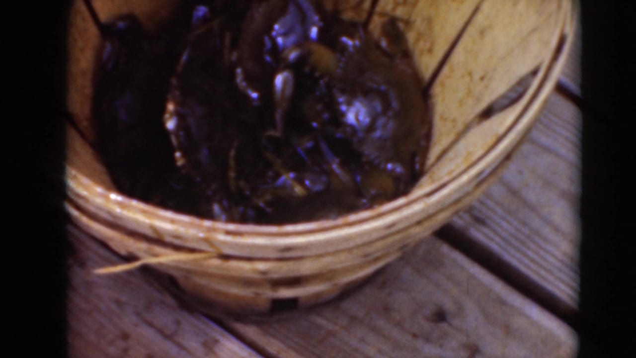 Dark wet crabs fill a wooden basket seen from above.