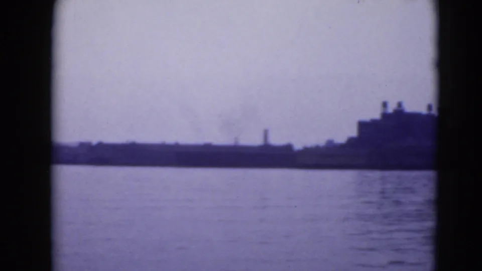 Distant Pennsylvania waterfront with open water, low shoreline structures, and a larger blocky building at the right edge.