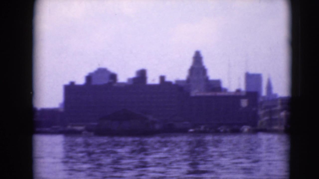 Soft waterfront view across a river with dark buildings and skyline shapes.