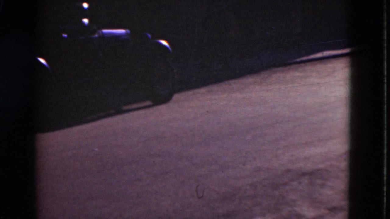 Paved road surface with the front of a parked car partly visible in shadow.