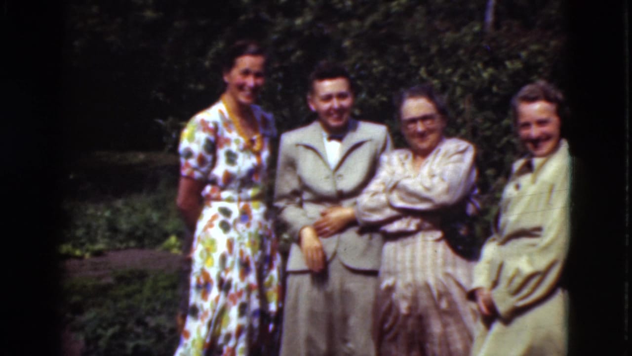 Four adults stand outdoors in formal clothing, smiling toward the camera.