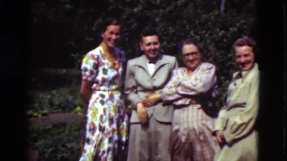 In Denmark 1975 home-movie footage, four well-dressed adults stand in a garden setting and smile toward the camera.