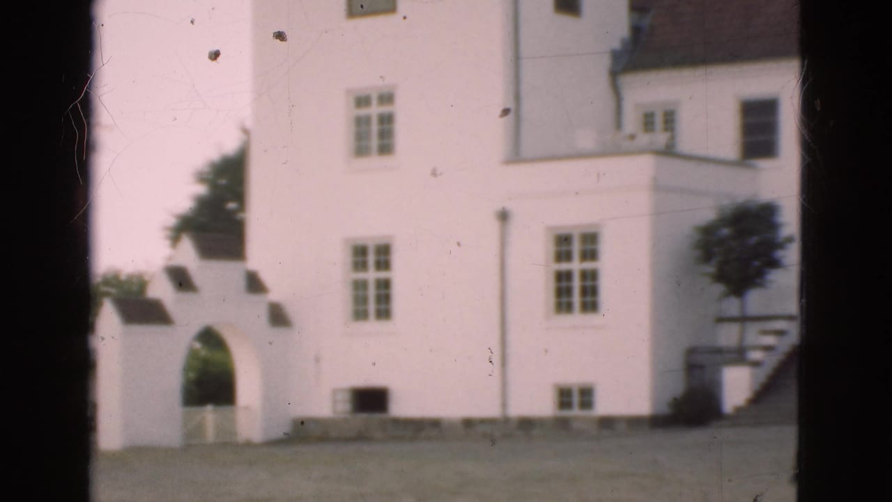 1975 Denmark 8mm frame with a white building, arched entrance, windows, roof sections, trees, and visible film wear.