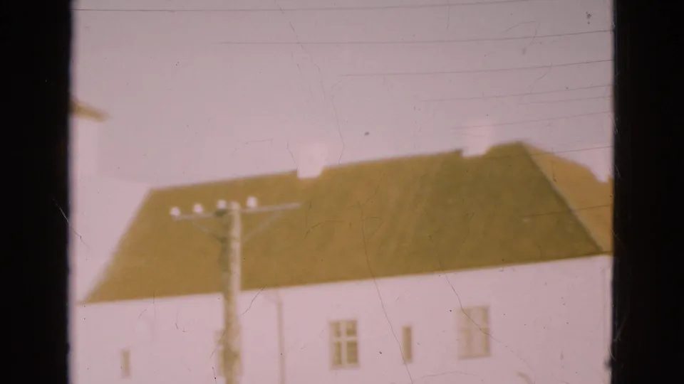 1975 Denmark 8mm frame with a brown roof, white facade, small windows, and a utility pole during a slow pan.
