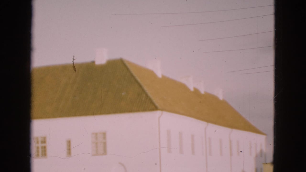 White farmhouse with green roof seen through 8mm frame edges.