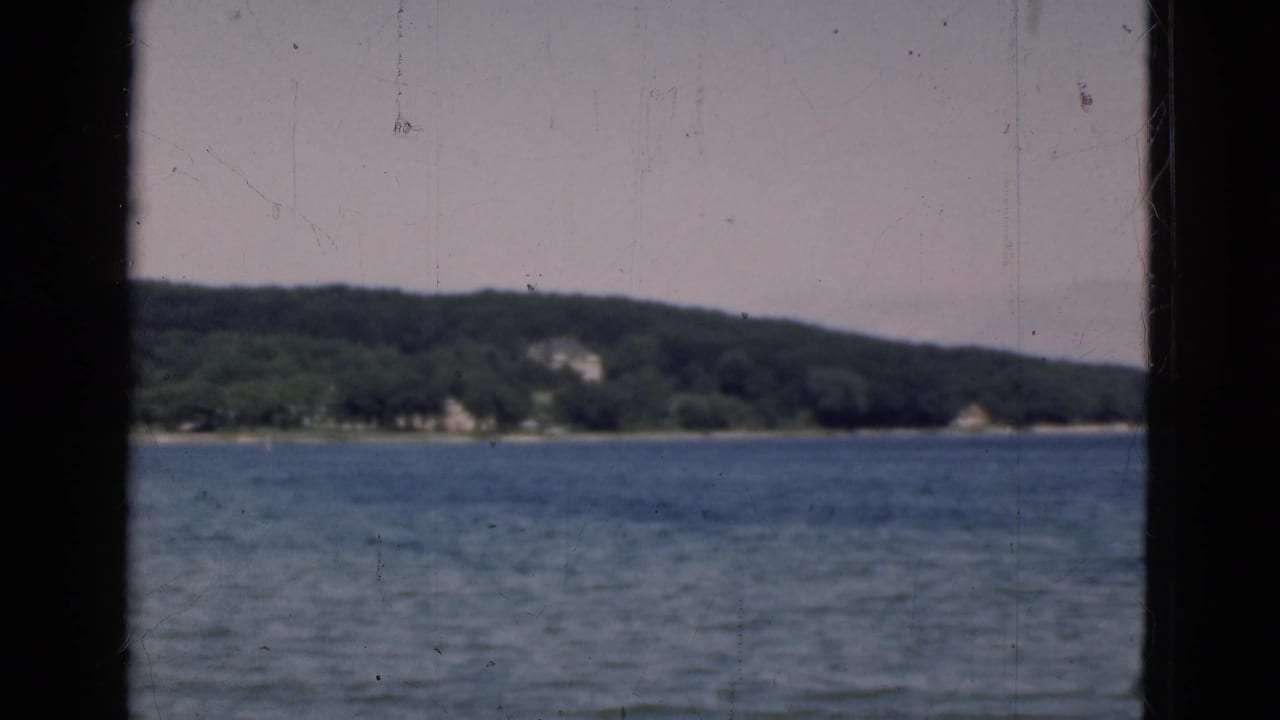 Soft lake horizon with distant trees and shoreline buildings behind a dark central bar.