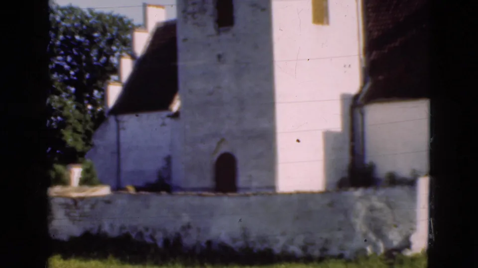1975 Denmark frame with the church wall, arched doorway, roof edge, trees, low wall, and visible 8mm scan borders.