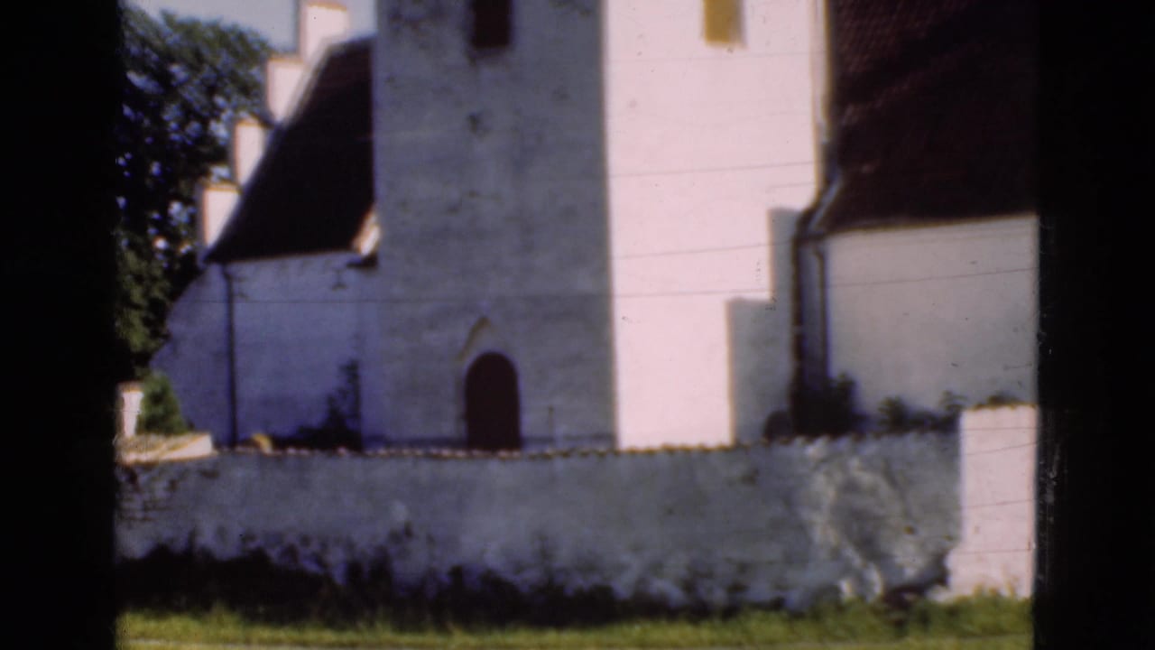 White church tower and arched doorway behind a low wall.