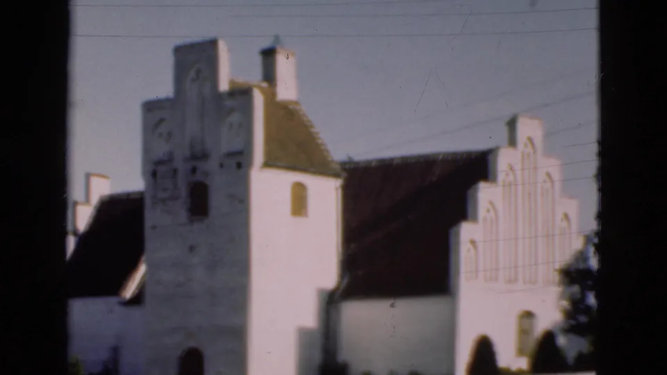 1975 Denmark 8mm frame showing a white church exterior with a tower, stepped gable, arched openings, and dark roof.