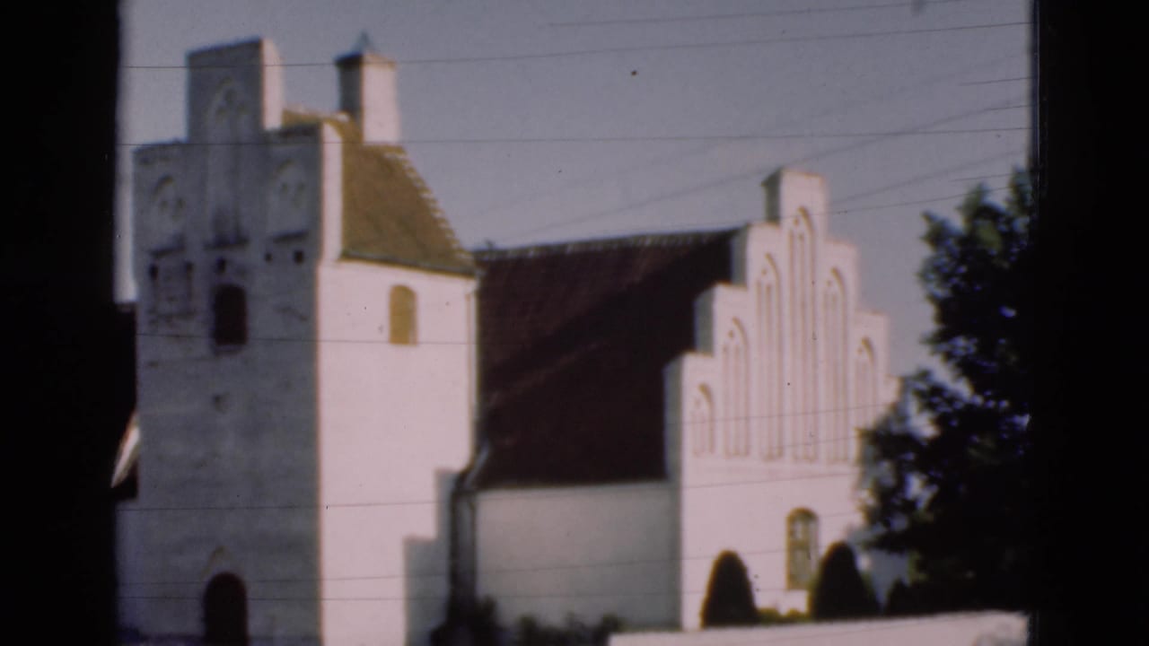 White church tower and stepped gable with trees at the right edge.