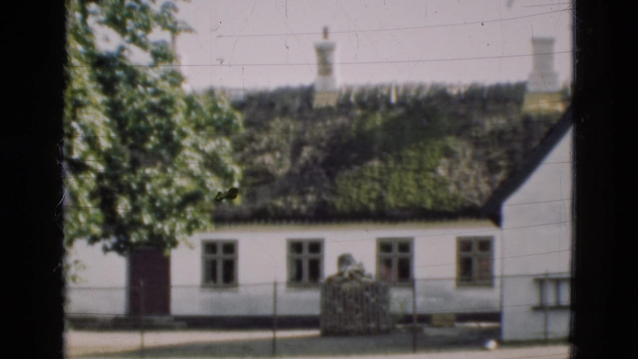 White house with dark thatched roof seen through a dark window frame.