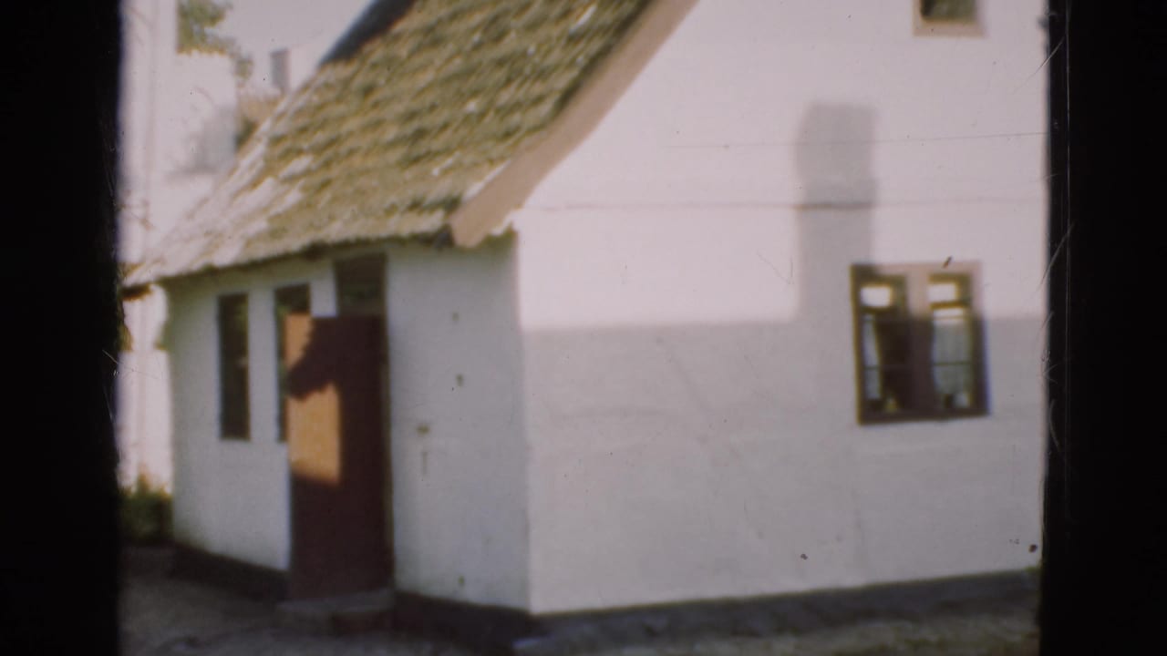 White house exterior with thatched roof, dark door, and small windows.