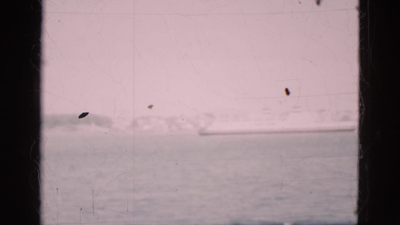 Harbor water and a distant ship framed by dark window bars.