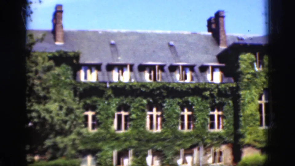 1975 Denmark 8mm frame showing a large ivy-covered house facade with tall windows, chimneys, roof dormers, and dark film-edge framing.