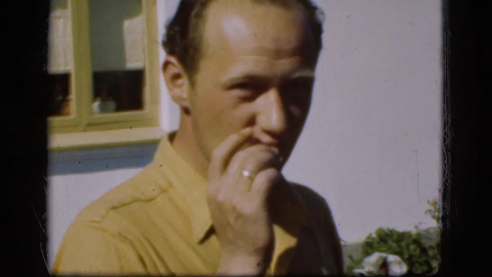 In the garden setting, the younger man turns toward the camera with his hand near his mouth, possibly holding a cigarette.