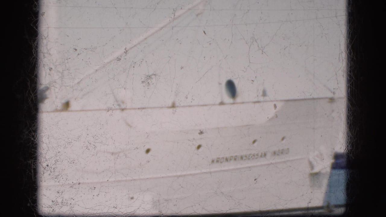 Close view of the ship's white side with partial name, portholes, rigging, and water at right.