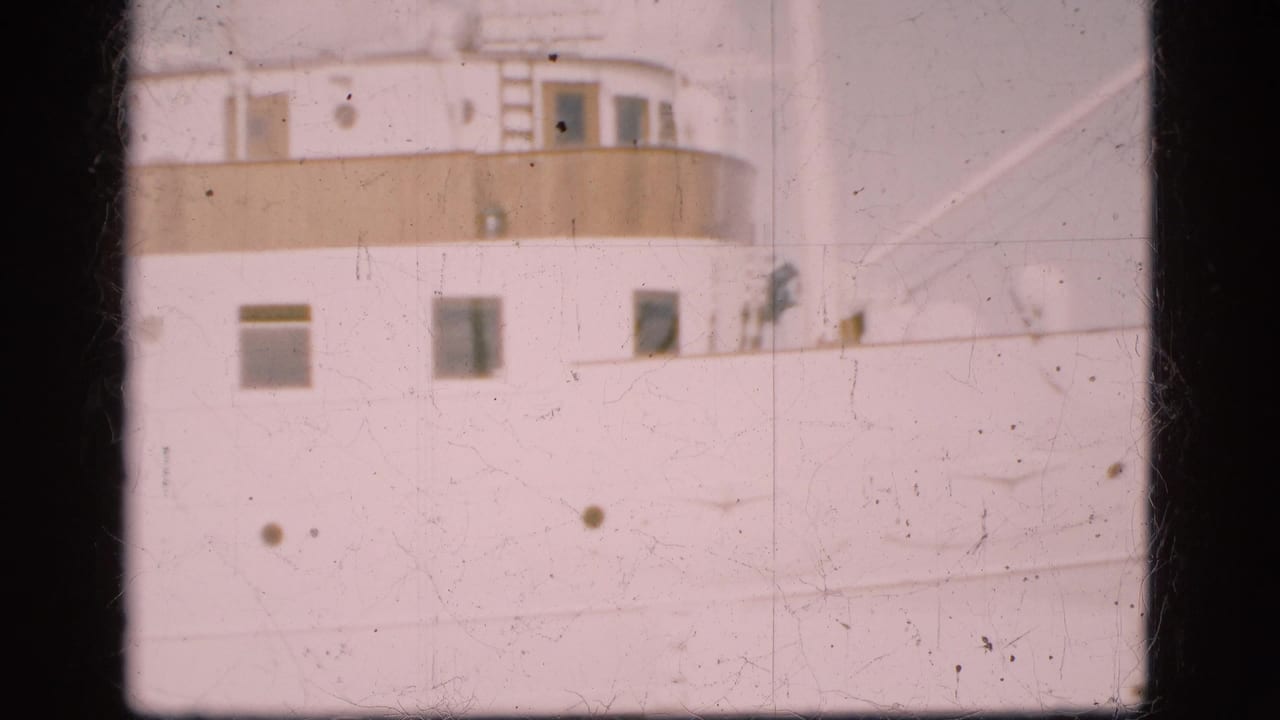 Close view of a white passenger ship side with windows, portholes and upper deck railings.