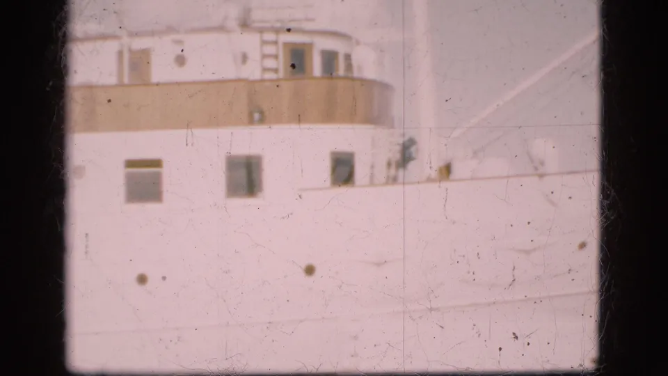 1975 Denmark 8mm frame showing the upper side of a large white passenger ship with windows, portholes and deck railings.