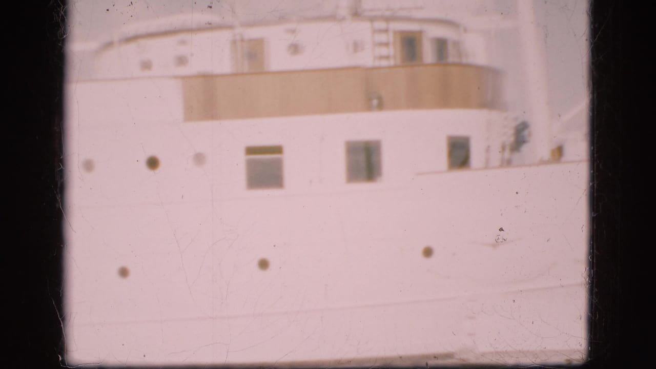 White ship exterior with portholes, rectangular windows and a band of upper deck railing.
