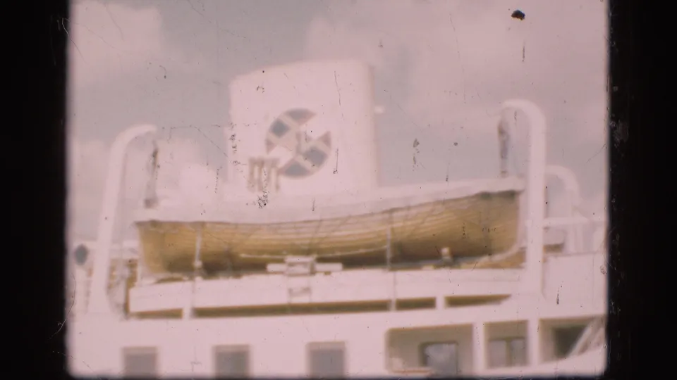 1975 Denmark 8mm frame showing a lifeboat secured on deck below a white funnel with a circular logo-like mark.