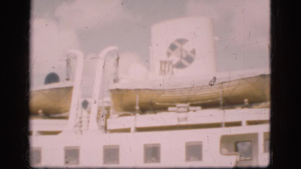 1975 Denmark 8mm frame with two lifeboats, white davits, railings and a funnel carrying a circular logo-like mark.