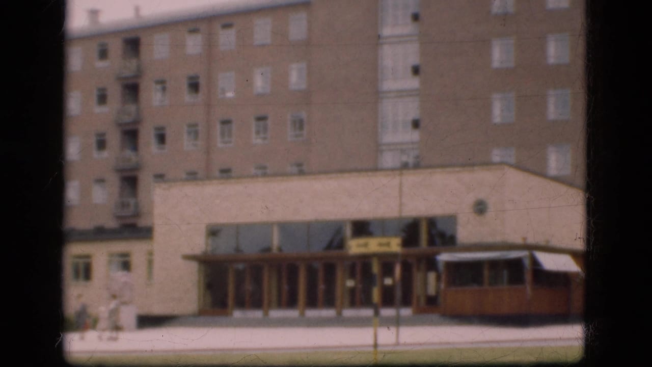 A large building facade and entrance with a vehicle near the curb.