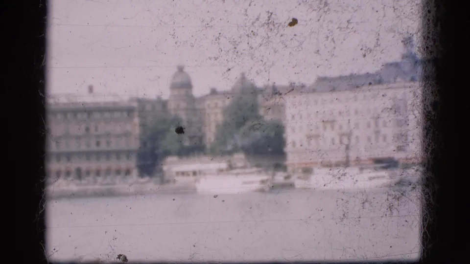 1975 Denmark 8mm frame showing a soft waterfront city view with boats and distant historic European-style buildings.