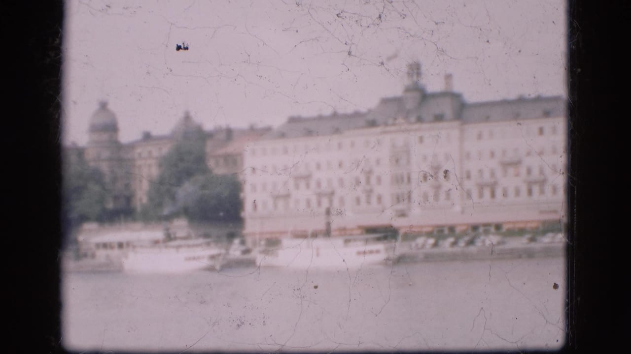 1975 Denmark 8mm frame with a soft-focus river view, moored boats, pale building facades, trees, and a distant dome.